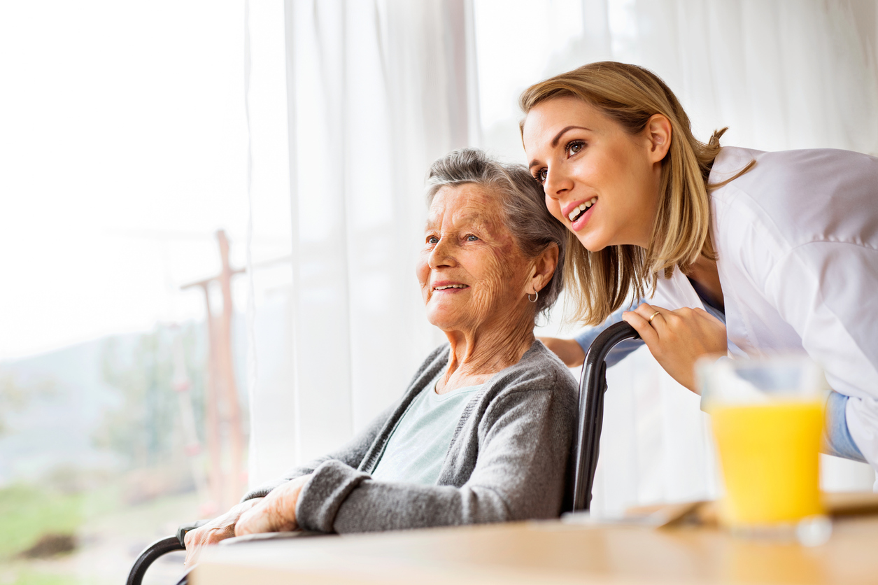 Health visitor and a senior woman during home visit. A nurse talking to an elderly woman in an wheelchair.